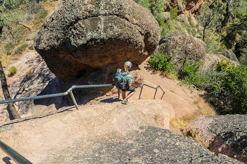 Female hiker climbing down the trail carved into the rock faces of Pinnacles National Park