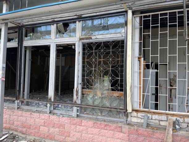 istock Close up of broken windows in old building. Windows with broken glasses in abandoned brick building. Concept of street riots 1326865101