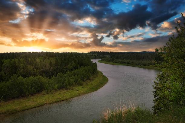 Sunrise Clouds Over The Red Deer River A bright cloudy sunrise sky shining bright over the Red Deer river in the summertime. alberta stock pictures, royalty-free photos & images