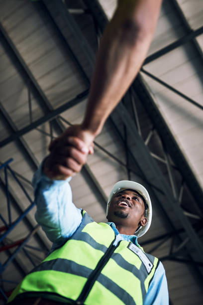 istock Shot of two builders shaking hands at a construction site 1326873281