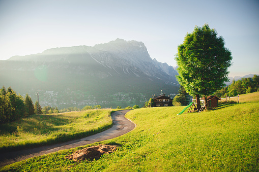 View of Cortina D'Ampezzo with Pomagagnon mountian the background and little pathway surrounded by field, Dolomites, Italy, South Tyrol.