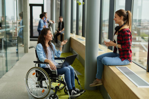 istock Disabled computer programmer discussing with female coworker in office hallway 1326880654