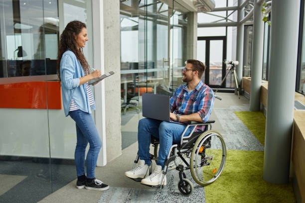 istock Disabled male computer programmer discussing with female coworker in office hallway 1326880764