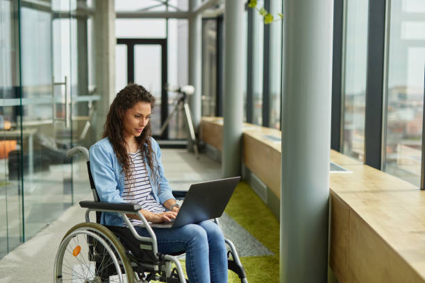 istock Disabled female IT worker in wheelchair working with laptop 1326880790