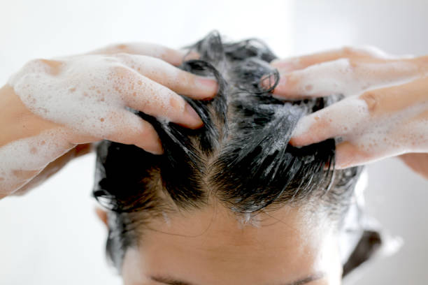 Woman is washing her hair with shampoo stock photo