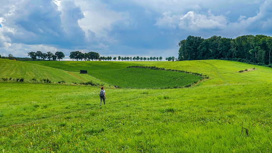 Wide shot of a hiker woman walking on the dutch meadow, province of Limburg