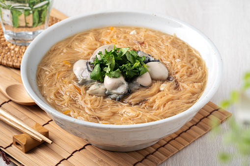 Homemade delicious juicy oyster vermicelli thin noodles in a bowl on wooden table background.