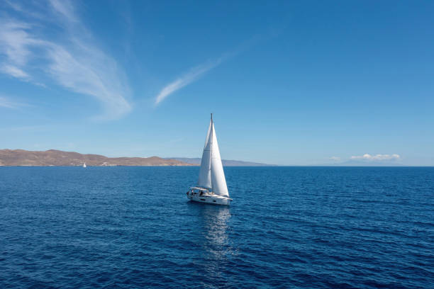 istock Sailing boat with open white sails, blue sky and rippled sea background 1326889178