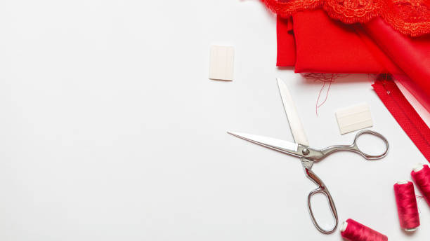 istock Tailoring concept. beautiful red satin fabric with sewing thread, scissors, chalk and spool on a white background. Top view. copy space 1326894838