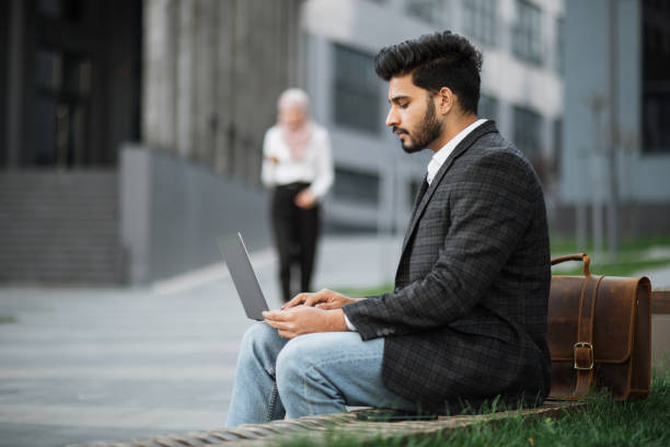 istock Arabian man working on laptop while woman in hijab on mobile 1326900710