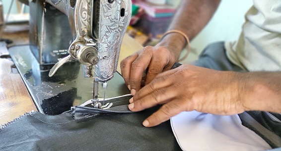 Hands close up of a tailor working with sewing machine