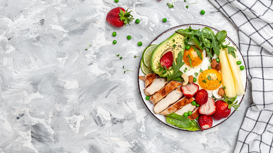 keto ketogenic diet Fried egg, avocado, strawberry, grilled chicken fillet, cheese, nuts and arugula, Ketogenic diet. Low carb high fat breakfast, top view,