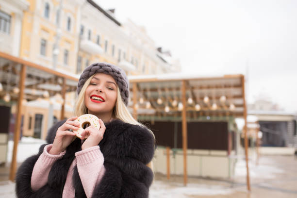 istock Cheerful young model holding delicious ginger cookie against light decoration at the Christmas fair in Kiev 1326905904