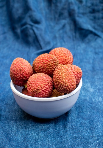 many ripe red unpeeled lychees - vertical food background