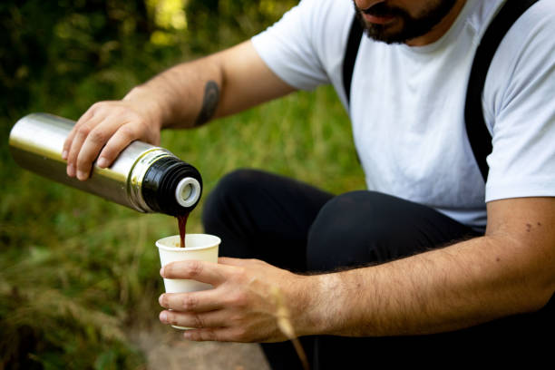 istock Young man pours a hot drink-tea or coffee from termos into cup in the forest 1326909925