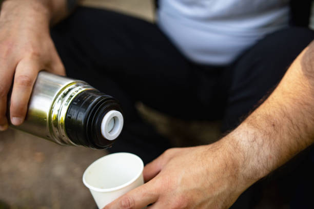 istock Young man pours a hot drink-tea or coffee from termos into cup in the forest 1326909929