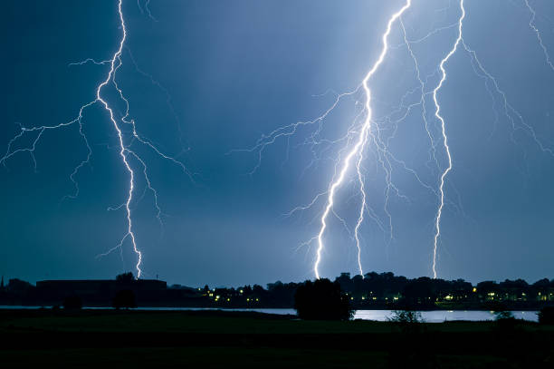 branched lightning strikes close to a river - flowing water flash imagens e fotografias de stock