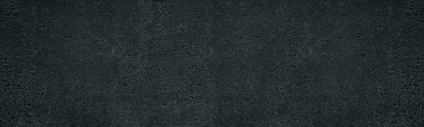 istock Black rough concrete panoramic texture. Cement with pebble wall panorama. Abstract dark gray wide background 1326917287