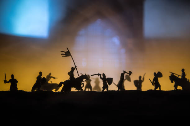 istock Medieval battle scene with cavalry and infantry. Silhouettes of figures as separate objects, fight between warriors on sunset foggy background. 1326918299