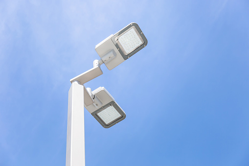 LED street lamp post glowing blue sky with white cloud background. Modern led lights in city
