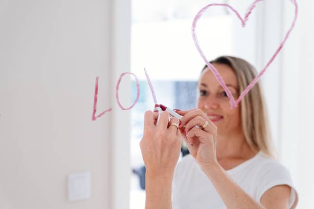 istock Romantic woman drawing heart on mirror by lipstick. 1326920172