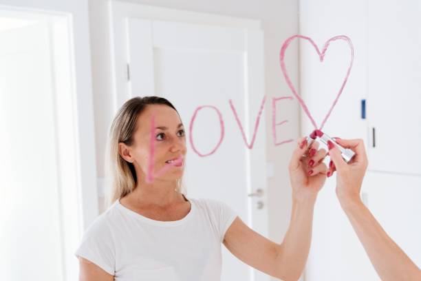 istock Romantic woman drawing heart on mirror by lipstick. 1326920225