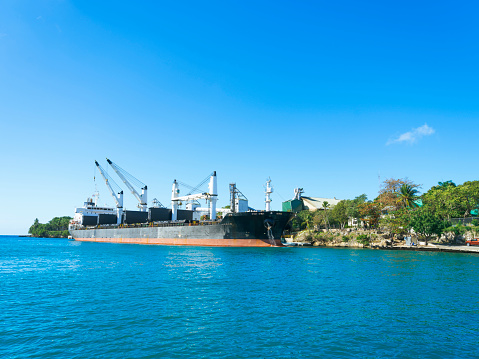 Ship at the harbor of La Romana, industrial port, construction cranes, mountain view, Dominican Republic