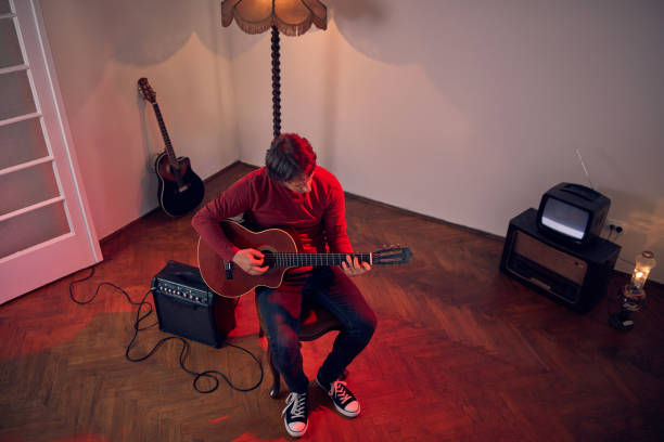 męski muzyk grający na gitarze akustycznej na wzmacniaczu w retro vintage roomie. - fingerstyle zdjęcia i obrazy z banku zdjęć