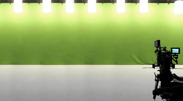 istock Camera and green screen studio in panorama view. Flood light hanging on ceiling. Green screen for chroma key technique. Video or film production equipment. Film industry. 1326927561