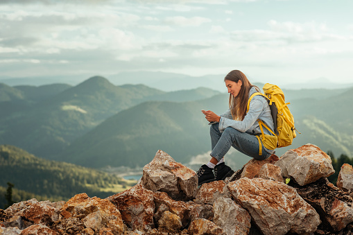 Young female with backpacker using phone while out on an adventurous in the mountains