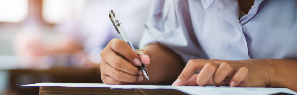 istock Students writing and reading exam answer sheets exercises in classroom of school with stress 1326929925