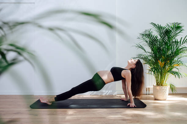 istock Side view on a pregnant woman practicing yoga alone, doing reverse plank 1326934587