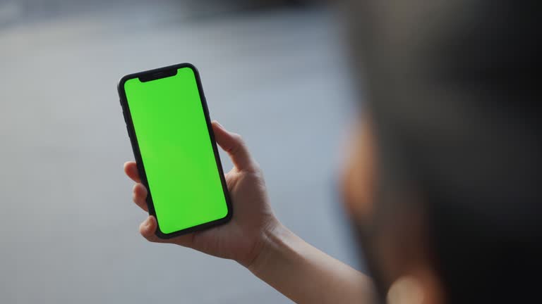 Woman holding phone , Green screen on phone in the city