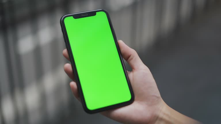 Woman holding phone , Green screen on phone in the city