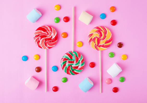 istock Three lollipops, multicolored candies and marshmallows on pink 1326940062