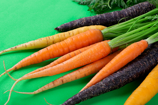 Bunches of fresh orange carrots, with kale to the side, on display at a farmer's market