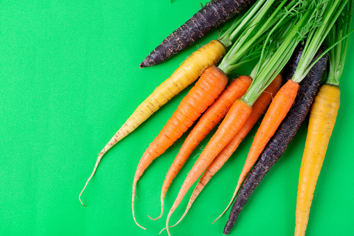 Orange, yellow and purple carrots on green. Organic vegetable