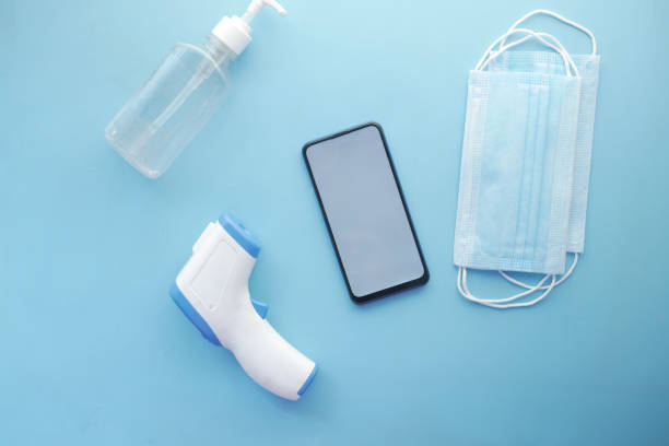 istock flat composition of smart phone, mask, thermometer and sanitizer on table 1326941884