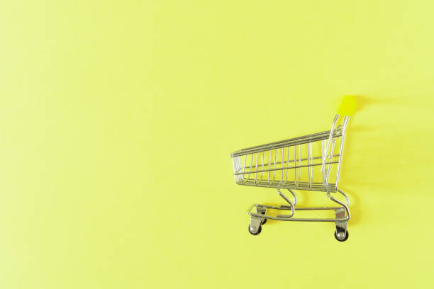 istock Empty shopping cart with yellow handle on light yellow background with space for text. 1326942147