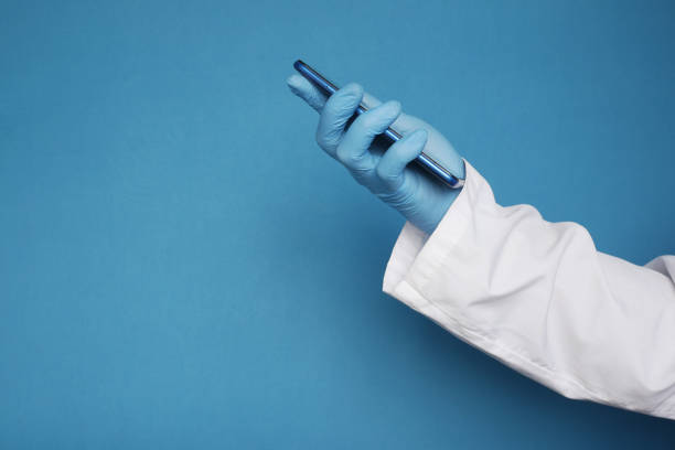 istock doctor's hand in protective gloves using a smartphone against blue background 1326942421