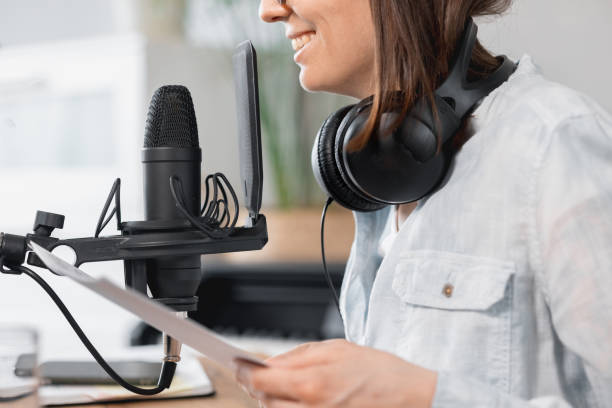 podcaster crea contenuti, la donna europea registra podcast con microfono e cuffie, donna caucasica in studio di registrazione registra voce per spot pubblicitari o audiolibri - mid adult audio foto e immagini stock