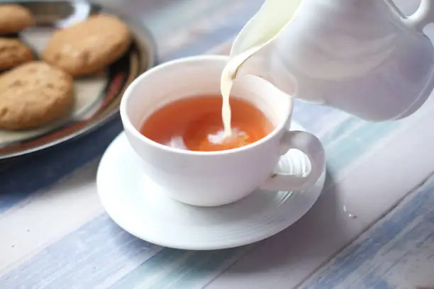 close up of pouring milk in a tea cup .