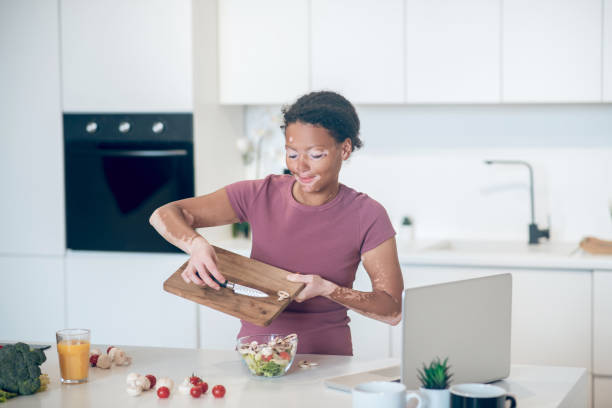 istock A dark-skinned woman cutting vegetables and looking involved 1326945589