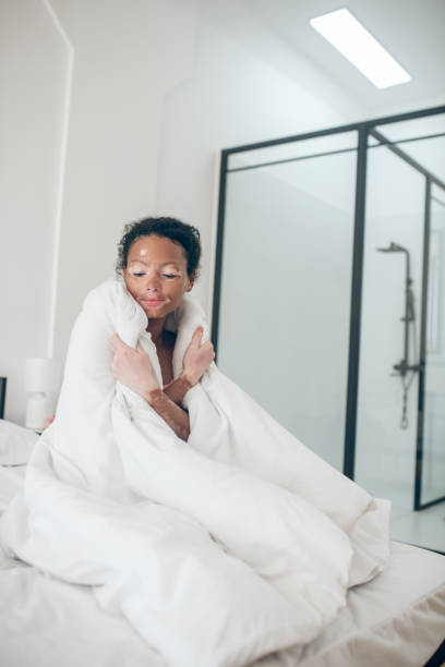 istock Young woman sitting in bed covered with blanket and feeling relaxed 1326946191