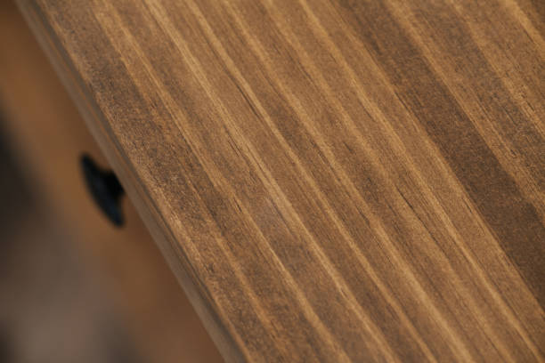 Deck of a wooden table close up. Rest is blurred. Drawer handle sticking