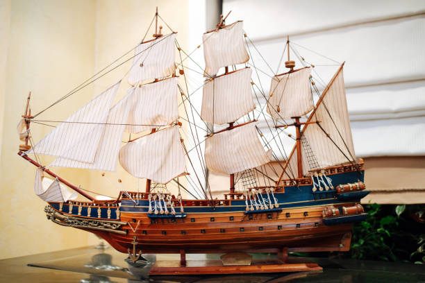 istock Wooden old sail ship model on a stand on a glass table. 1326946450