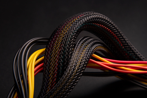 Black Cable with snake skin. Black braided wires in bundle on black background. Braided Sleeving. Data line protection. Wire Flame-retardant nylon tube