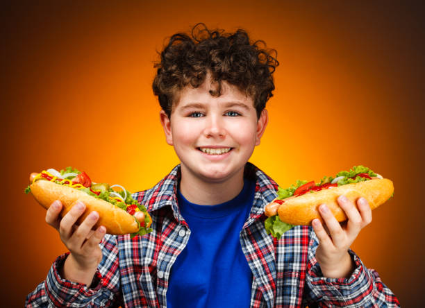 istock Boy holding two hot dogs 1326950656
