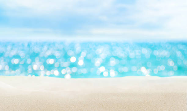 Seascape and sandy beach. Defocused sea water surface glittering on the sun. Sandy beach and Blurred sunlight abstract bokeh on blue turquoise sea and sky background glittering sea stock pictures, royalty-free photos & images