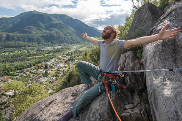 male mountain climber arms outstretched on mountain top - conquering adversity wilderness area aspirations achievement imagens e fotografias de stock